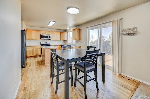 dining room featuring baseboards, visible vents, and light wood finished floors