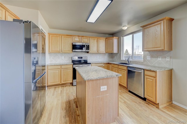 kitchen featuring appliances with stainless steel finishes, light brown cabinets, a sink, and light wood-style flooring