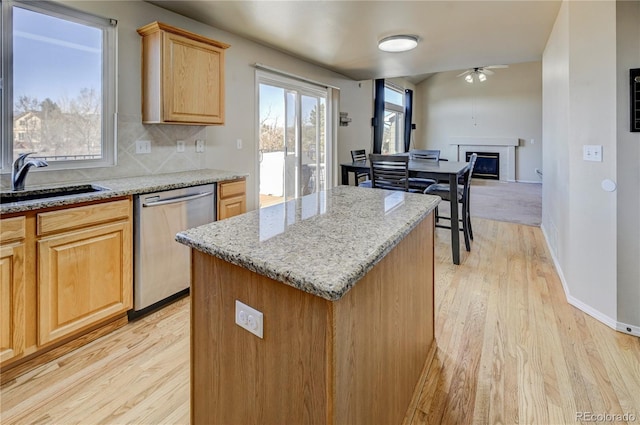 kitchen featuring a wealth of natural light, a glass covered fireplace, a sink, and stainless steel dishwasher