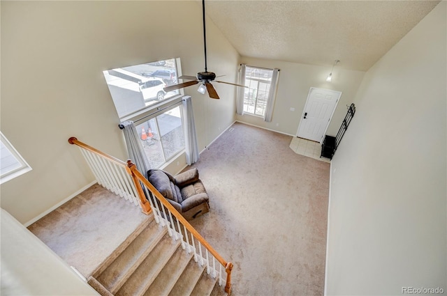 stairway featuring a textured ceiling, carpet, a ceiling fan, and baseboards