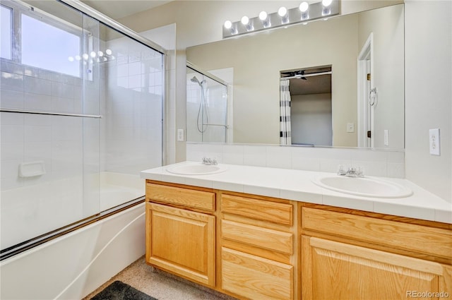 bathroom with bath / shower combo with glass door, a sink, and double vanity