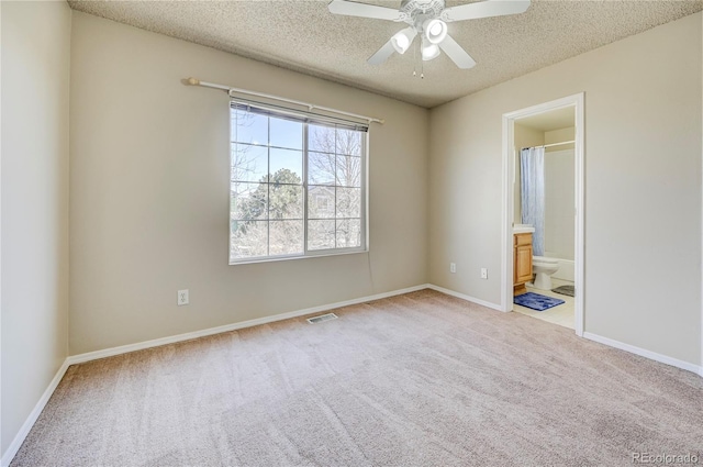 empty room with a textured ceiling, ceiling fan, carpet flooring, visible vents, and baseboards