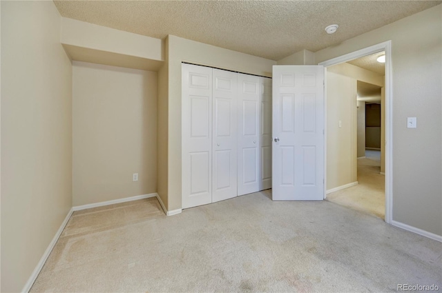 unfurnished bedroom featuring a textured ceiling, a closet, carpet, and baseboards