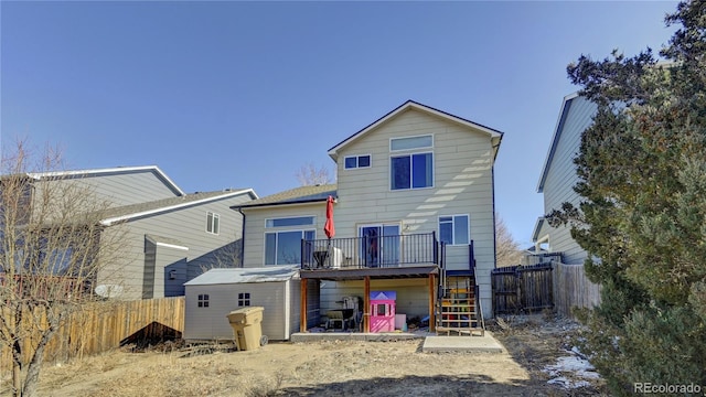 rear view of property with a deck, an outdoor structure, a fenced backyard, and stairs