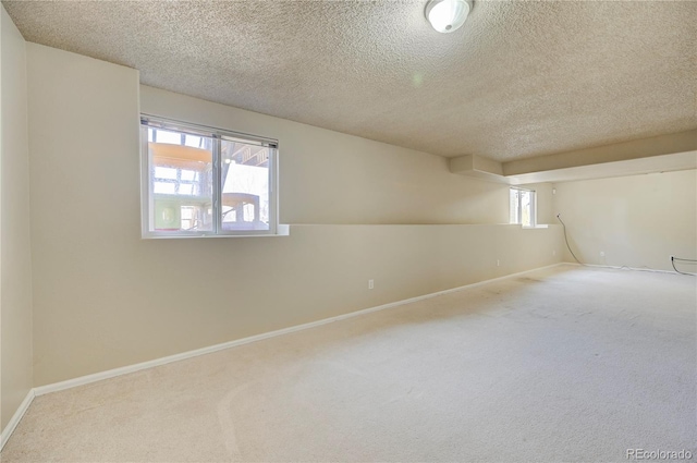 carpeted spare room with a textured ceiling and baseboards