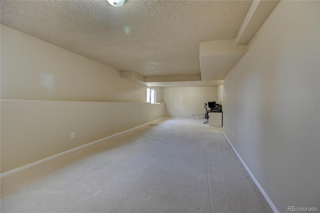 interior space featuring a textured ceiling, carpet flooring, and baseboards