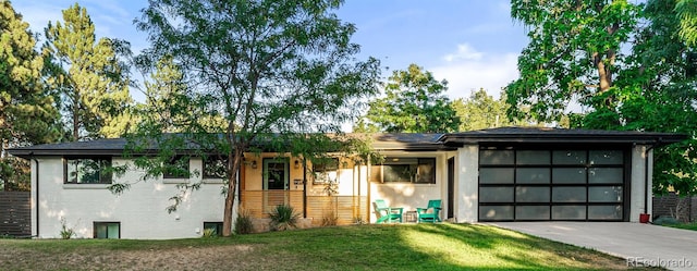 ranch-style home featuring a garage, a front yard, concrete driveway, and brick siding