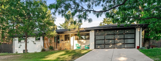 ranch-style house featuring an attached garage, a front lawn, and concrete driveway