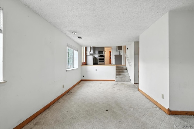 2527 S Ouray Way, Aurora, CO 80013 - unfurnished living room with a textured ceiling, carpet, and stairway
