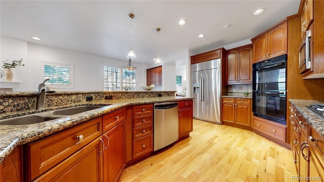 203 S Jackson St, Denver, CO 80209 - kitchen with appliances with stainless steel finishes, light wood-style floors, decorative backsplash, pendant lighting, and light stone countertops