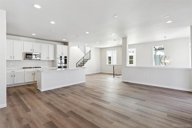 kitchen with gas stovetop, hanging light fixtures, white cabinets, and light hardwood / wood-style floors