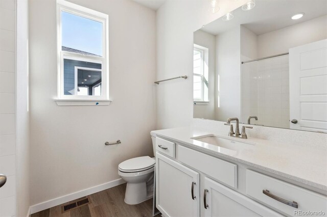 bathroom with wood-type flooring, toilet, vanity, and a shower