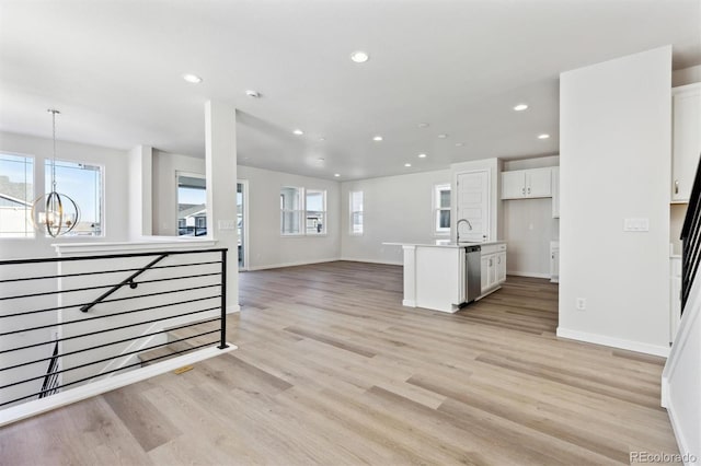 kitchen featuring white cabinetry, a notable chandelier, a kitchen island with sink, and dishwasher