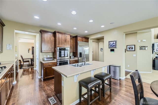 16059 E Grass River Pl, Parker, CO 80134 - kitchen with stainless steel appliances, dark wood-type flooring, light countertops, a center island with sink, and recessed lighting