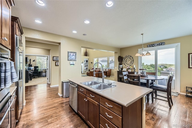 16059 E Grass River Pl, Parker, CO 80134 - kitchen with stainless steel appliances, wood finished floors, light countertops, decorative light fixtures, and recessed lighting