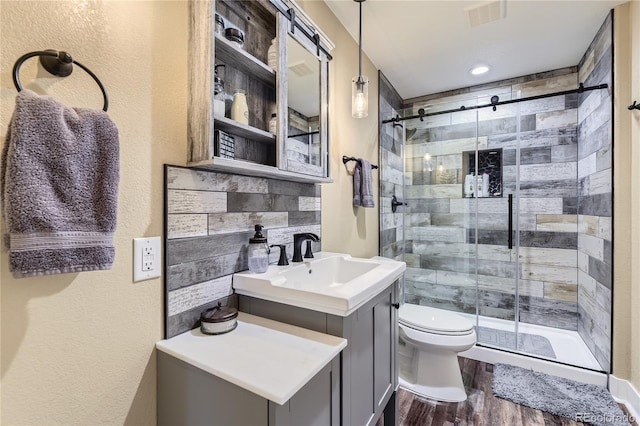16059 E Grass River Pl, Parker, CO 80134 - bathroom with wood finished floors, a shower stall, vanity, and a textured wall