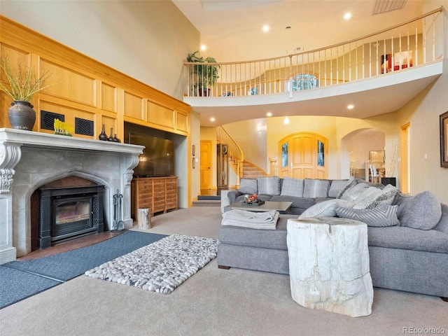 living area featuring arched walkways, recessed lighting, stairs, and carpet