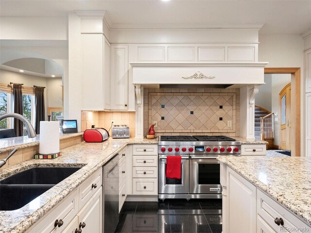 kitchen with tasteful backsplash, stainless steel appliances, dark tile patterned floors, sink, and white cabinets