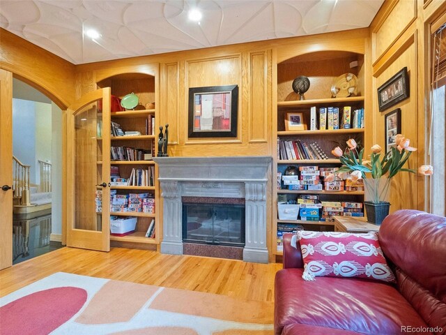 living room with built in shelves and hardwood / wood-style flooring