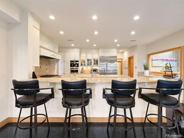 kitchen with light stone counters, stainless steel appliances, tasteful backsplash, and a breakfast bar