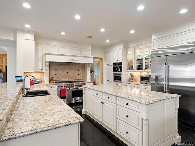 kitchen featuring a kitchen island, a toaster, high quality appliances, recessed lighting, and a sink