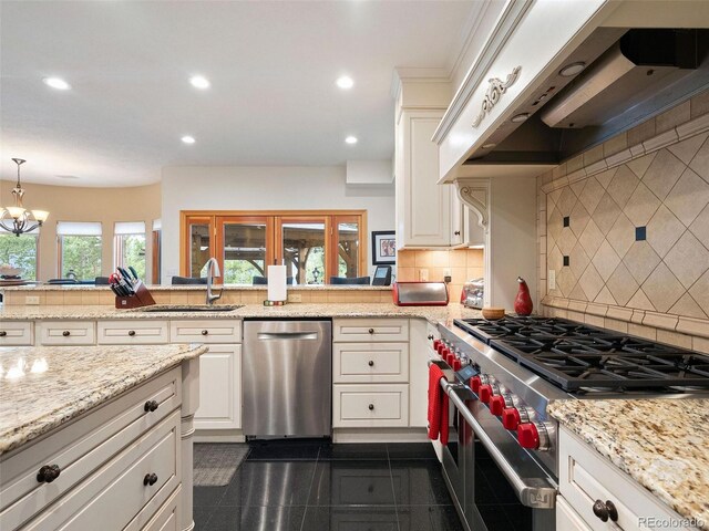 kitchen with tasteful backsplash, stainless steel appliances, an inviting chandelier, dark tile patterned floors, and sink