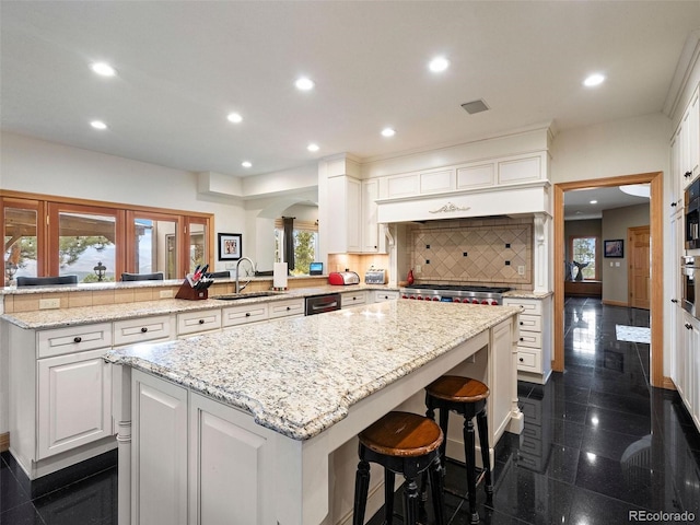 kitchen with kitchen peninsula, sink, dark tile patterned floors, decorative backsplash, and a breakfast bar area