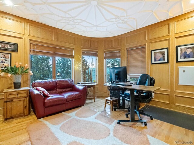 home office featuring light wood-type flooring and wood walls