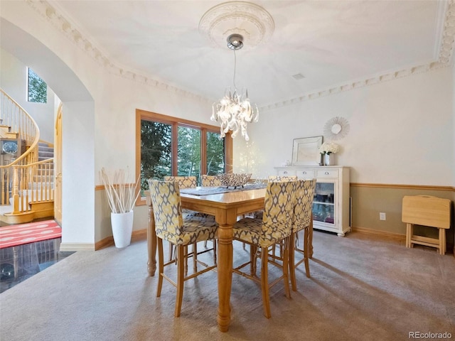 dining space featuring carpet floors, arched walkways, an inviting chandelier, and stairs