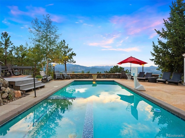 view of pool with a mountain view, a pool with connected hot tub, and a patio area