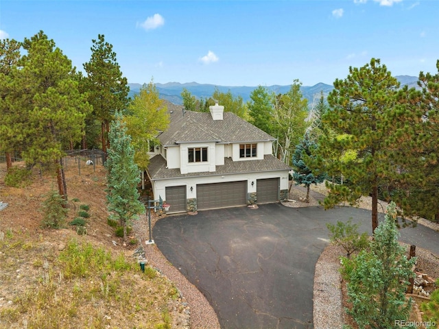 view of front of house with a mountain view, driveway, a chimney, and an attached garage