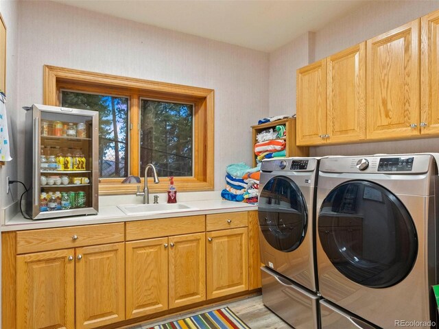 clothes washing area featuring washer and dryer, light hardwood / wood-style flooring, cabinets, and sink