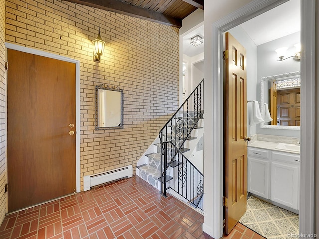 entrance foyer with beamed ceiling, brick wall, sink, and baseboard heating