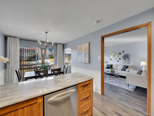 kitchen featuring dishwasher, hanging light fixtures, a notable chandelier, light stone counters, and light hardwood / wood-style flooring