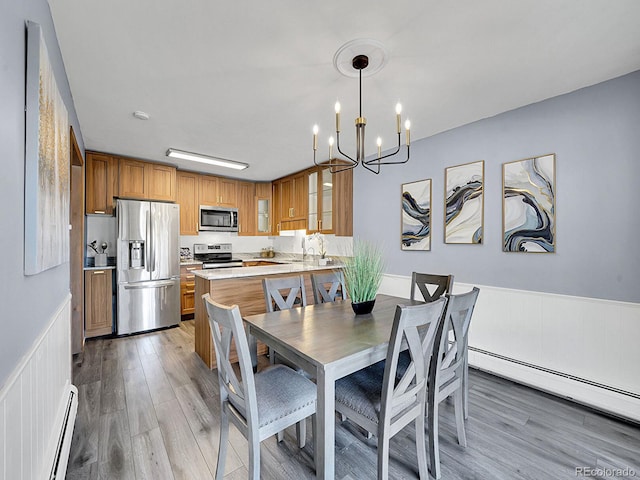 dining space featuring baseboard heating, a chandelier, and hardwood / wood-style floors