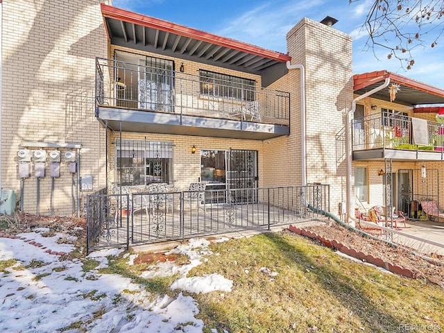 snow covered house with a balcony, a patio, and central air condition unit