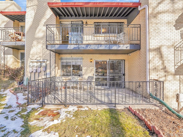 snow covered house featuring a balcony and a patio area