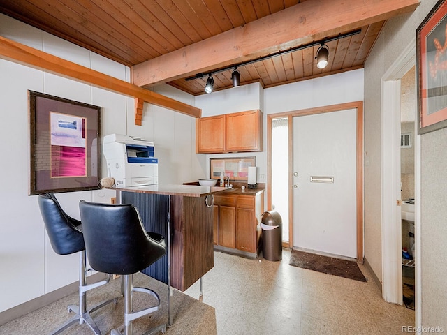 kitchen with beam ceiling, wood ceiling, a kitchen breakfast bar, and rail lighting