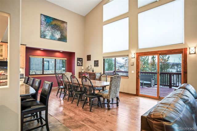 dining area with a high ceiling, light wood-style floors, and baseboards