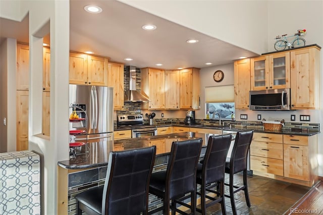 kitchen featuring a sink, wall chimney range hood, light brown cabinets, and stainless steel appliances