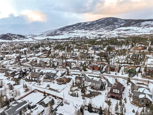 snowy aerial view featuring a residential view and a mountain view