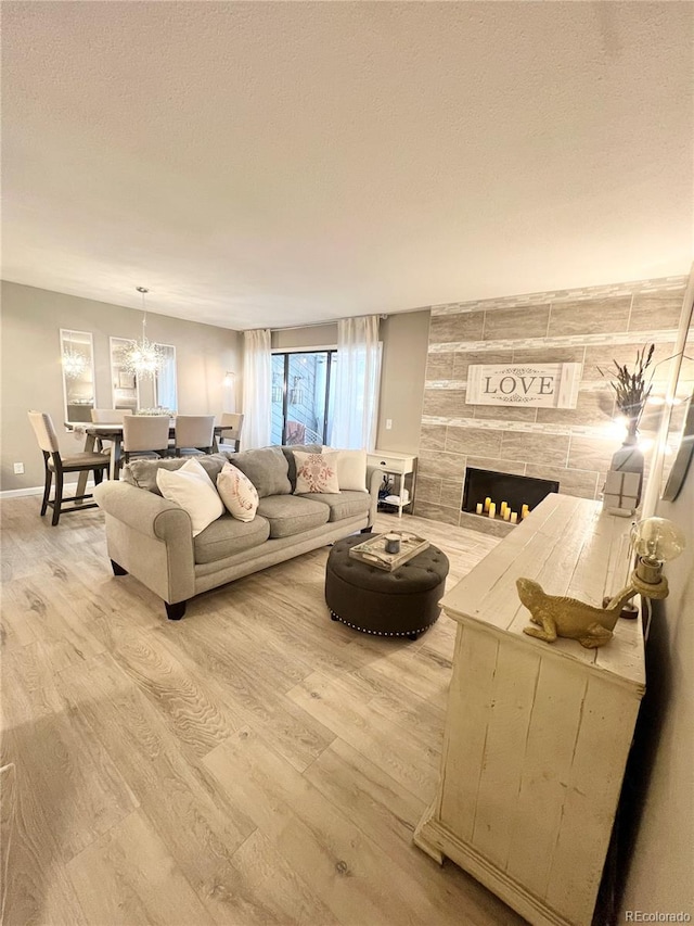 living room with an inviting chandelier, a tiled fireplace, and light hardwood / wood-style flooring