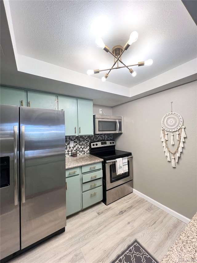 kitchen with backsplash, green cabinetry, stainless steel appliances, and light wood-type flooring