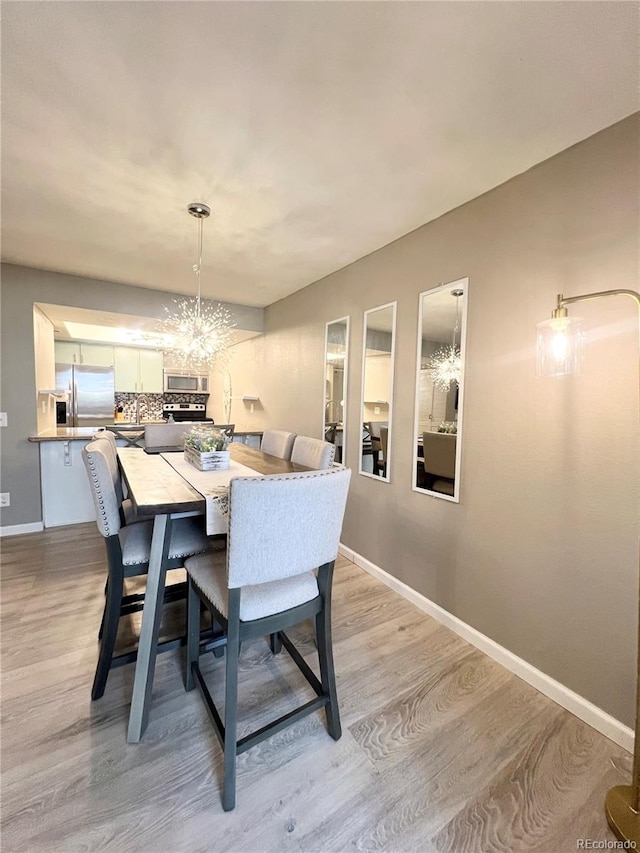 dining room with light wood-type flooring and a chandelier