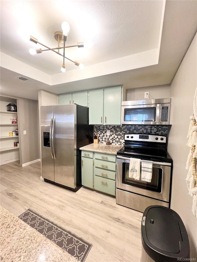 kitchen featuring decorative backsplash, stainless steel appliances, a textured ceiling, light hardwood / wood-style flooring, and green cabinets