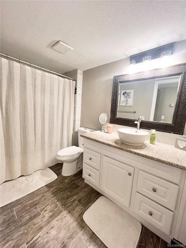 bathroom featuring vanity, hardwood / wood-style floors, toilet, and a textured ceiling