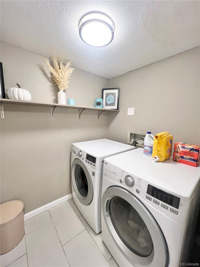 washroom featuring a textured ceiling, light tile patterned floors, and washing machine and dryer