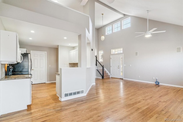 kitchen featuring high vaulted ceiling, white cabinets, hanging light fixtures, light hardwood / wood-style flooring, and ceiling fan