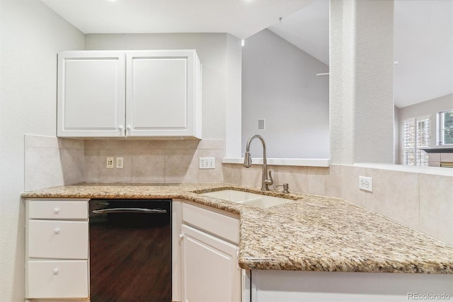 kitchen with light stone counters, sink, white cabinets, and black dishwasher