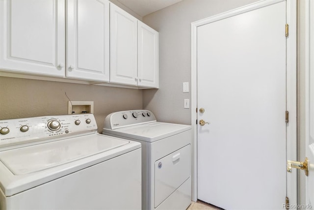 washroom with washing machine and clothes dryer and cabinets